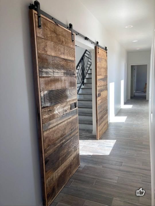 Pair of reclaimed wood sliding barn doors on a black steel track in a hallway